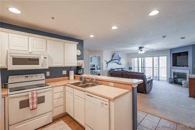 kitchen with sink, kitchen peninsula, light colored carpet, white appliances, and ceiling fan