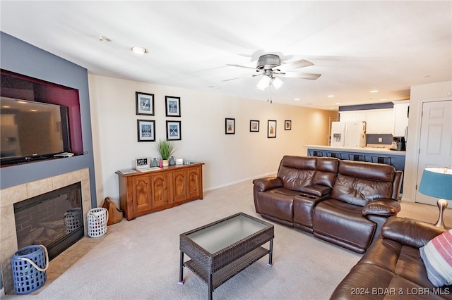 carpeted living room with ceiling fan and a tile fireplace