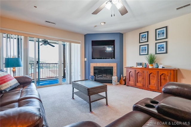 living room with ceiling fan, light colored carpet, and a tile fireplace