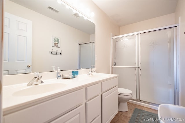 bathroom with vanity, toilet, tile patterned floors, and a shower with shower door