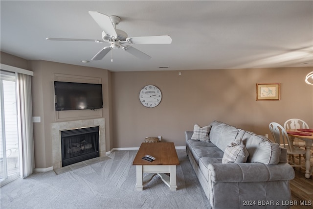 living room featuring light hardwood / wood-style flooring, ceiling fan, and a tile fireplace