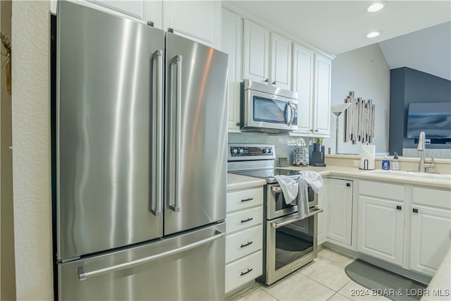 kitchen featuring sink, white cabinets, stainless steel appliances, backsplash, and light tile patterned floors