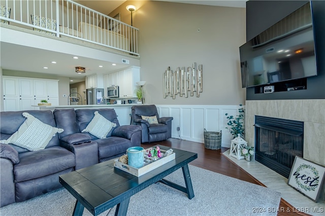 living room with a tile fireplace, light hardwood / wood-style flooring, and high vaulted ceiling