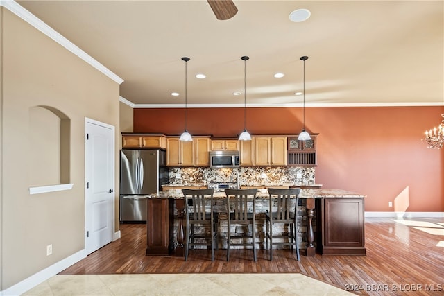 kitchen with hanging light fixtures, light stone counters, a breakfast bar area, stainless steel appliances, and a center island with sink