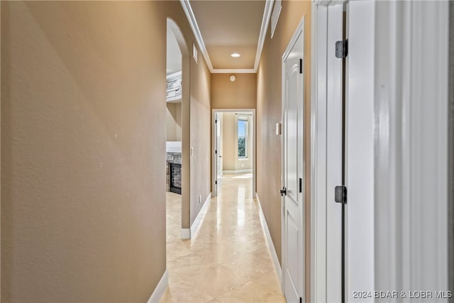 hallway featuring ornamental molding and light tile patterned floors