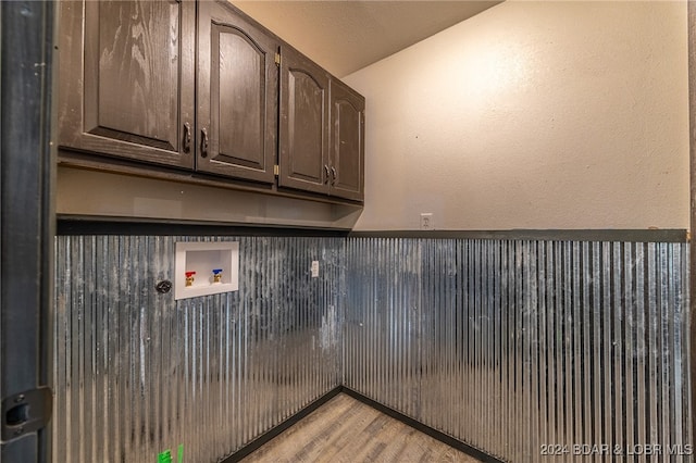 washroom with hookup for a washing machine, hardwood / wood-style floors, and cabinets