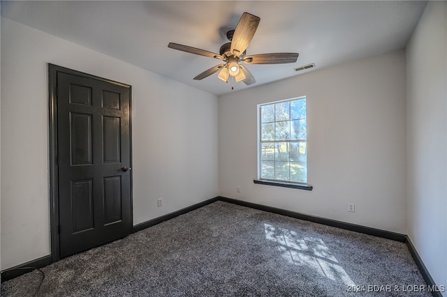 spare room featuring dark carpet and ceiling fan