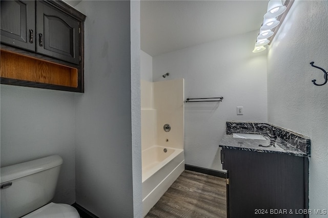 full bathroom featuring washtub / shower combination, hardwood / wood-style floors, vanity, and toilet