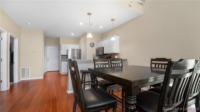 dining space with baseboards, visible vents, wood finished floors, and recessed lighting