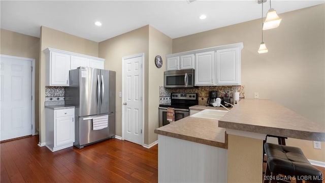 kitchen with appliances with stainless steel finishes, a sink, a peninsula, and dark wood-style floors