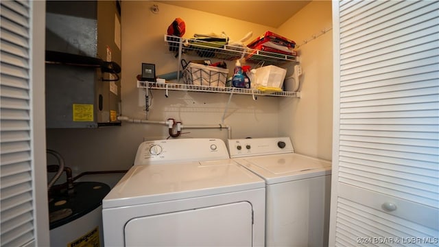 clothes washing area with laundry area, water heater, and washer and clothes dryer