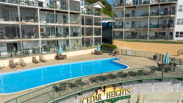 community pool with a patio area and fence