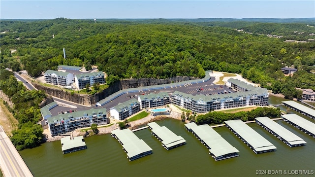 birds eye view of property featuring a water view and a wooded view