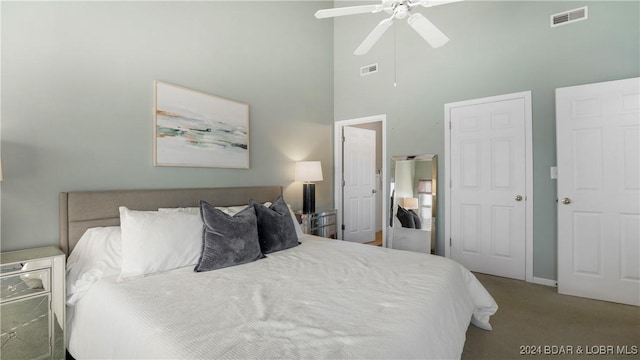 bedroom featuring a towering ceiling, a ceiling fan, visible vents, and carpet flooring