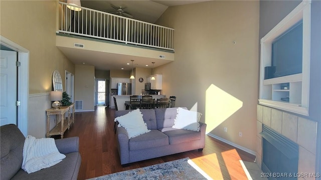 living room featuring baseboards, visible vents, a high ceiling, and wood finished floors