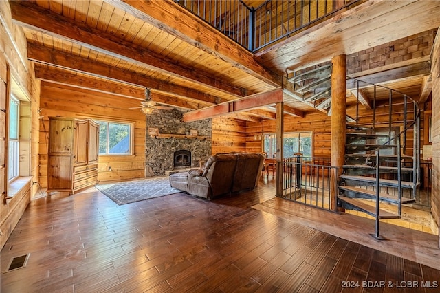 unfurnished living room featuring hardwood / wood-style floors, wood walls, ceiling fan, a fireplace, and wood ceiling