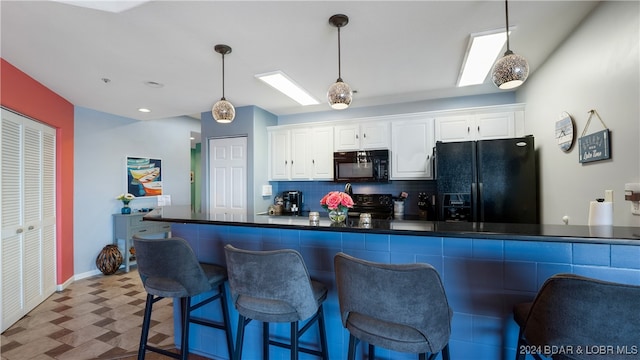 kitchen with white cabinets, a breakfast bar area, decorative light fixtures, and black appliances