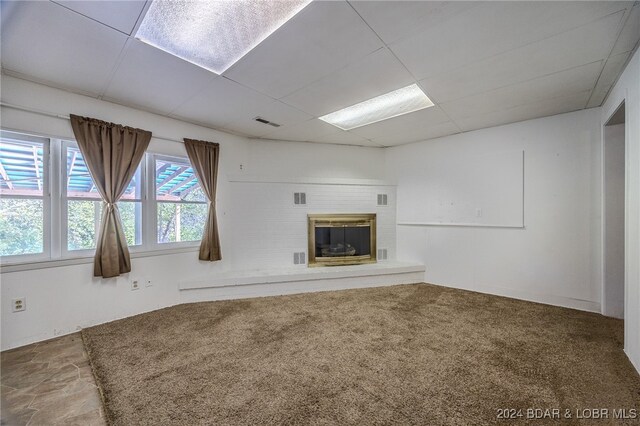 unfurnished living room featuring a brick fireplace and carpet flooring