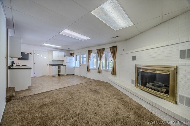 unfurnished living room with light carpet, a fireplace, and a paneled ceiling