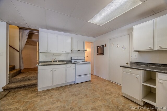 kitchen featuring white cabinets, electric range, a paneled ceiling, and sink