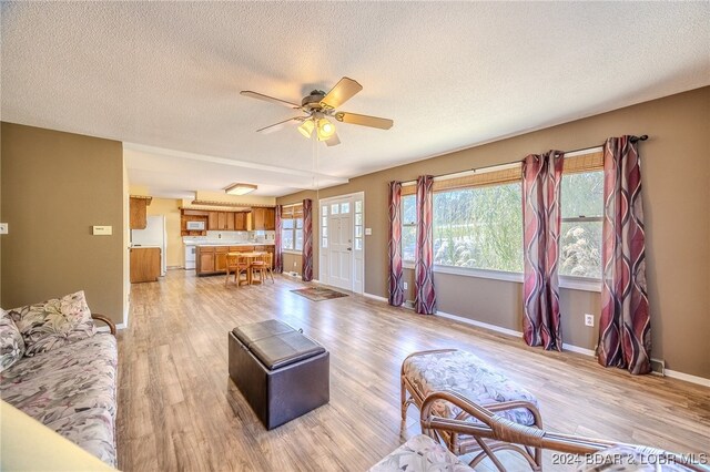 living room featuring light hardwood / wood-style floors, plenty of natural light, ceiling fan, and a textured ceiling