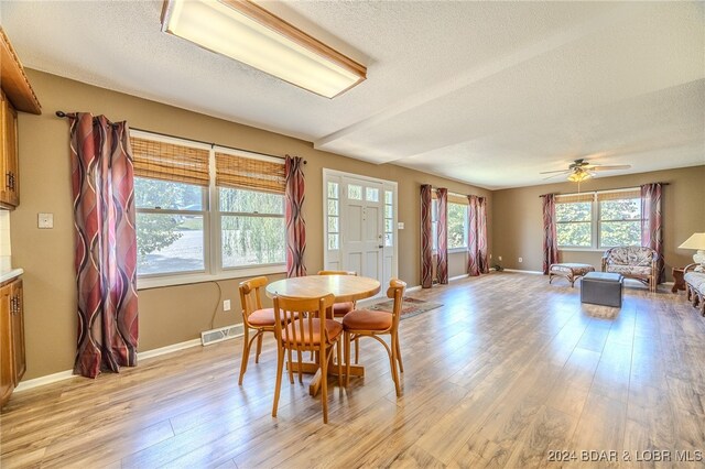 dining space with ceiling fan, a textured ceiling, and light wood-type flooring