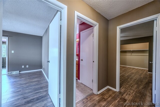 corridor with a textured ceiling and dark wood-type flooring