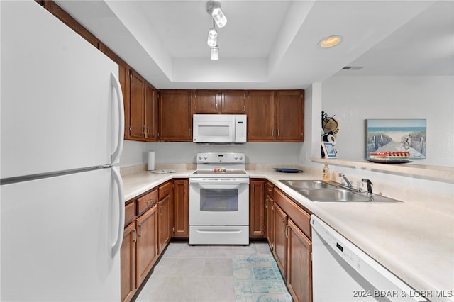 kitchen with white appliances, a raised ceiling, light tile patterned floors, and sink