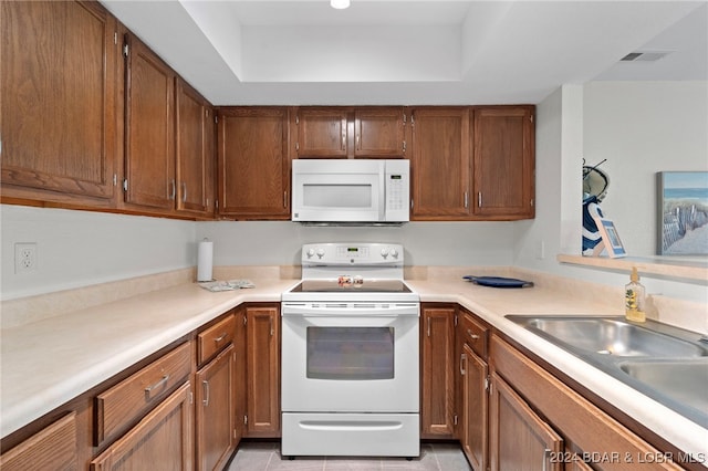 kitchen featuring white appliances, light tile patterned floors, and sink