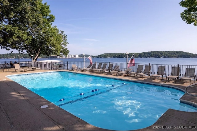 view of swimming pool with a patio area and a water view