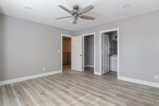 unfurnished bedroom with light hardwood / wood-style flooring, a closet, connected bathroom, and ceiling fan