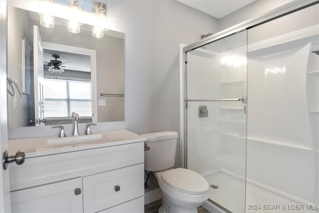 bathroom with ceiling fan, a shower with door, vanity, and toilet