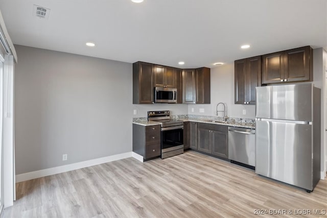 kitchen featuring light hardwood / wood-style flooring, dark brown cabinets, sink, stainless steel appliances, and light stone countertops