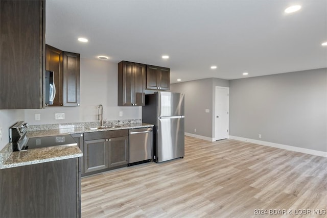 kitchen featuring light stone counters, sink, stainless steel appliances, and light hardwood / wood-style flooring