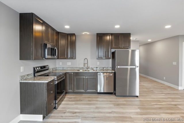 kitchen featuring light stone counters, sink, stainless steel appliances, and light hardwood / wood-style flooring