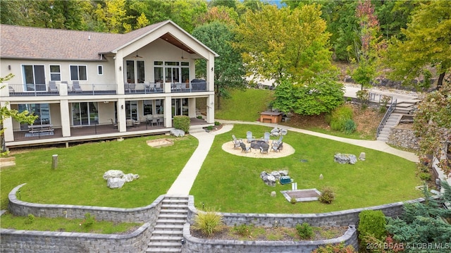 rear view of house with a balcony, a yard, a patio area, and an outdoor fire pit