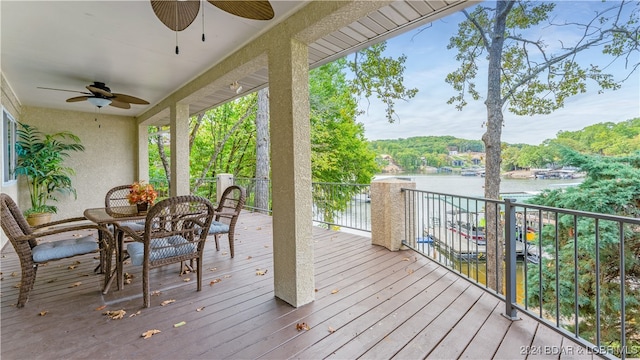 wooden deck with a water view and ceiling fan