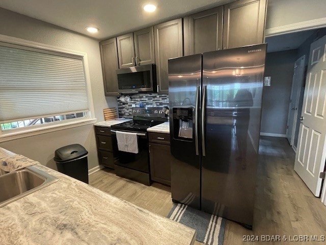 kitchen featuring appliances with stainless steel finishes, sink, light hardwood / wood-style flooring, and tasteful backsplash