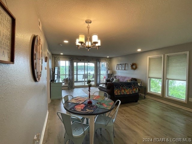 dining space with a notable chandelier, a textured ceiling, and hardwood / wood-style flooring