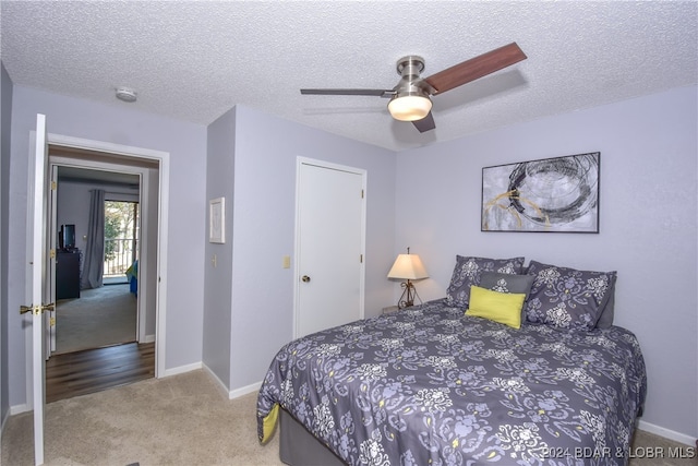 bedroom with ceiling fan, carpet floors, and a textured ceiling