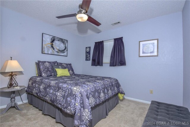 bedroom featuring ceiling fan, light colored carpet, and a textured ceiling