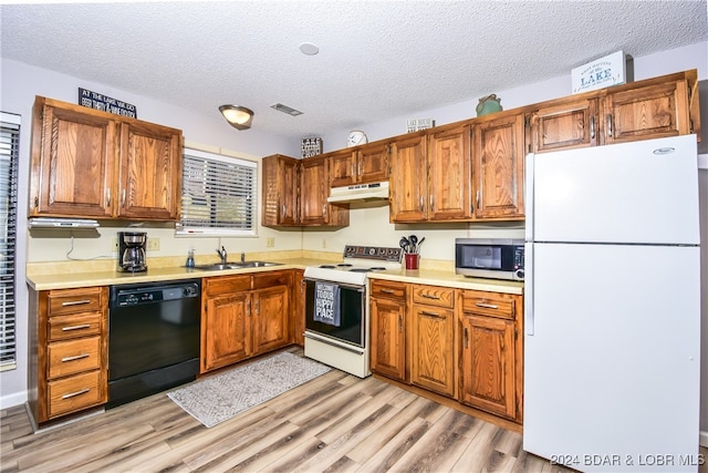 kitchen with a textured ceiling, light wood-type flooring, sink, and white appliances