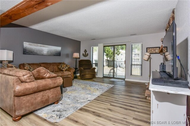 living room with a textured ceiling, beamed ceiling, and hardwood / wood-style floors