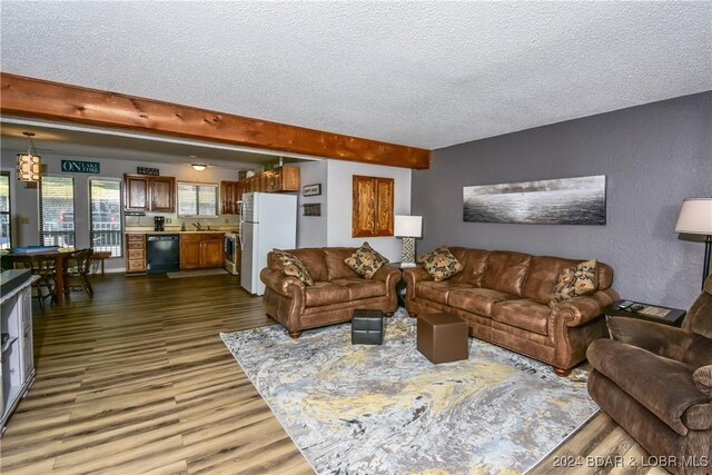 living room with a textured ceiling, dark hardwood / wood-style floors, and beam ceiling