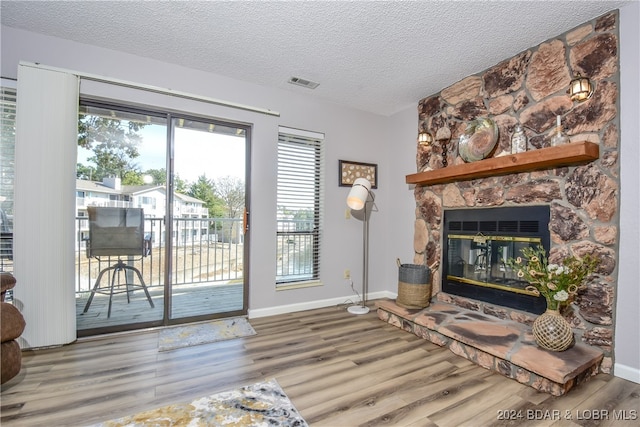 living room featuring hardwood / wood-style flooring, a fireplace, and a textured ceiling