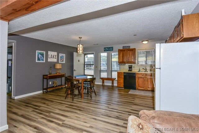 kitchen featuring pendant lighting, white refrigerator, sink, black dishwasher, and hardwood / wood-style floors