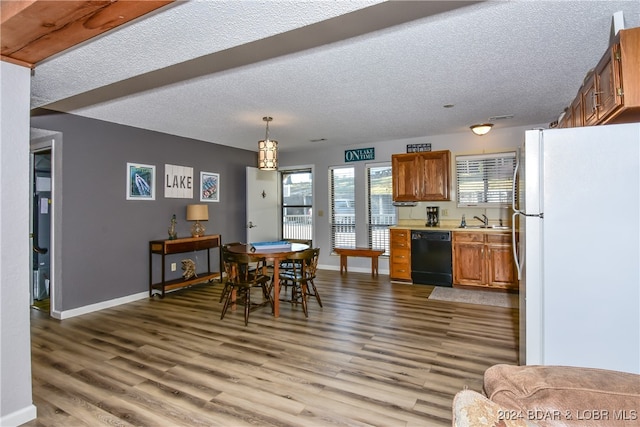 kitchen featuring hanging light fixtures, dishwasher, white fridge, wood-type flooring, and sink