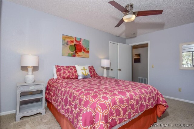 carpeted bedroom featuring a closet, a textured ceiling, and ceiling fan