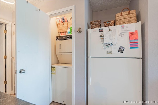 kitchen with white refrigerator, stacked washer and clothes dryer, and a textured ceiling