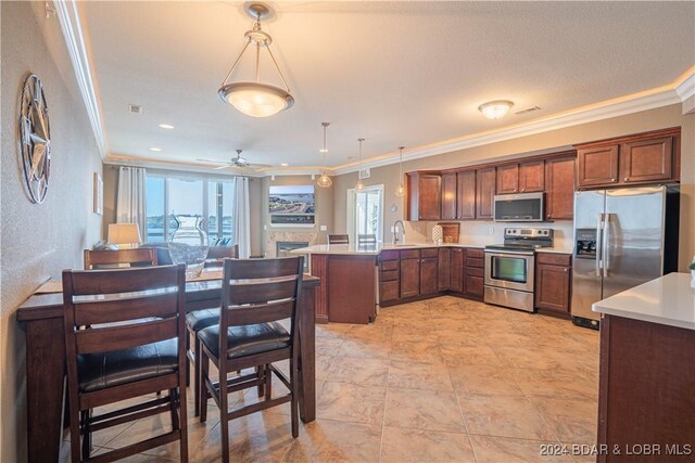 kitchen featuring kitchen peninsula, stainless steel appliances, hanging light fixtures, and crown molding